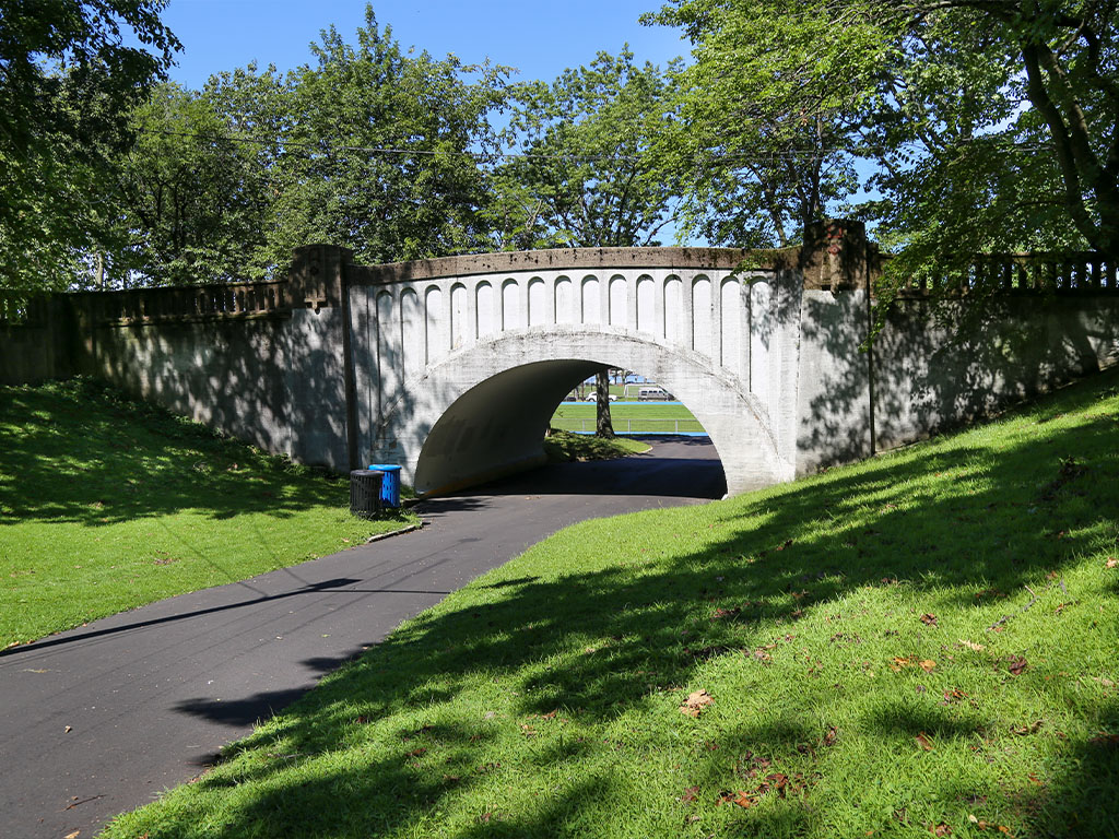Archway bridge in Stephen R. Gregg Park leading to a pathway, surrounded by lush greenery, highlighting local landmarks near Uforia Dispensary.