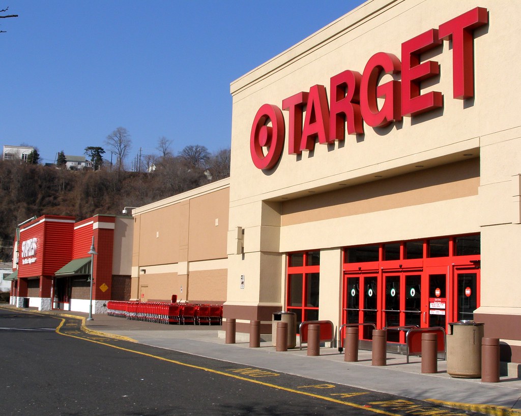 Target store exterior with prominent red signage, shopping carts lined up outside, and clear blue sky in the background, representing convenient shopping experience.