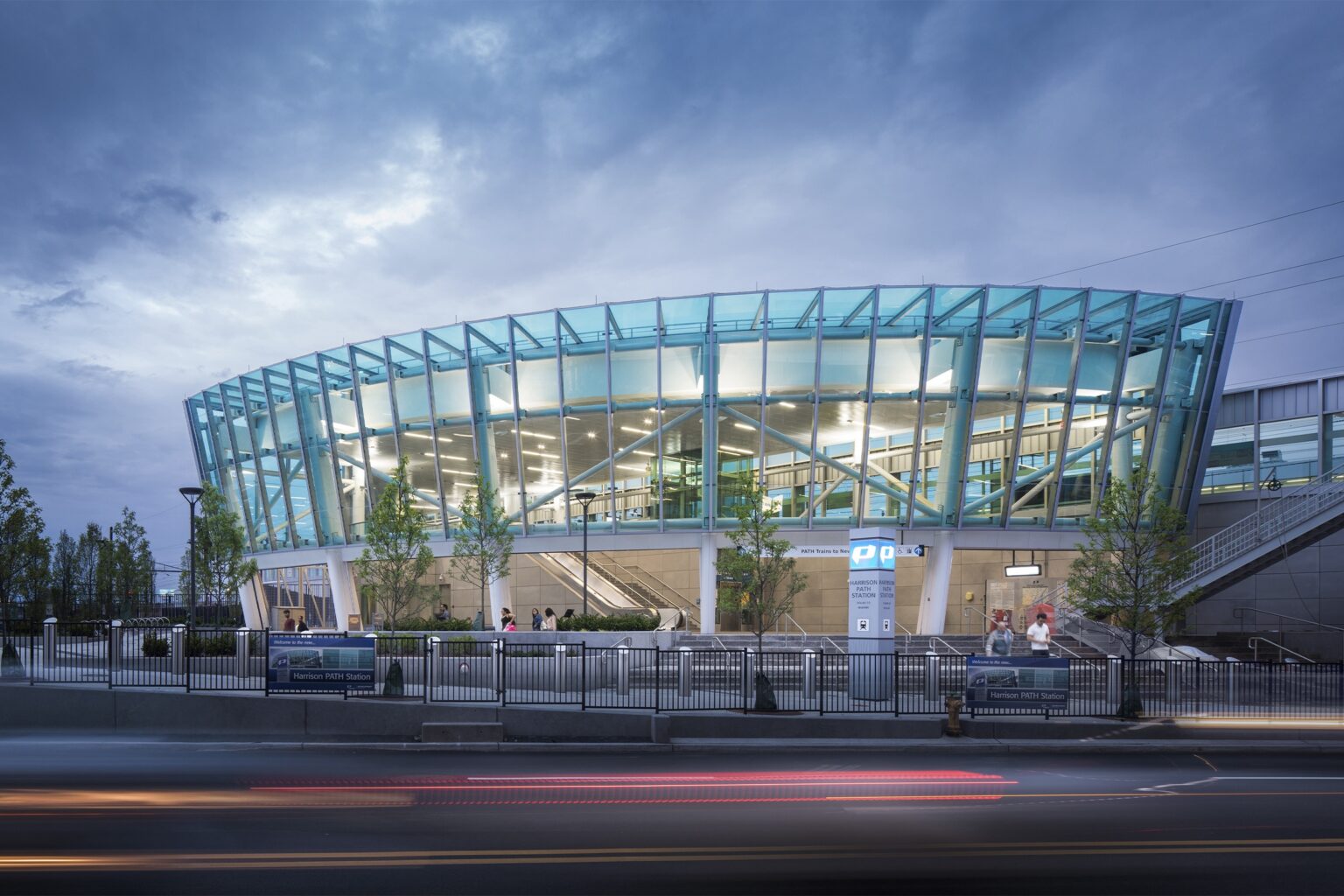 Harrison PATH Station exterior with modern glass architecture, featuring signage and landscaping, located near Uforia Dispensary in Harrison, NJ.