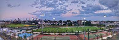 Panoramic view of Berry Lane Park in Jersey City, featuring sports fields, tennis courts, and the skyline of Manhattan in the background, illustrating a community space near Uforia Dispensary.