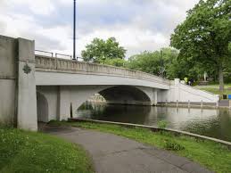 Bridge over water with grassy banks and walking path, near Uforia Dispensary in Harrison, NJ, highlighting accessibility for cannabis consumers.