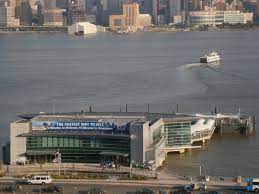 Port Imperial Ferry Terminal in Weehawken, NJ, with a ferry departing on the Hudson River, surrounded by city skyline, emphasizing accessibility to Uforia Dispensary.