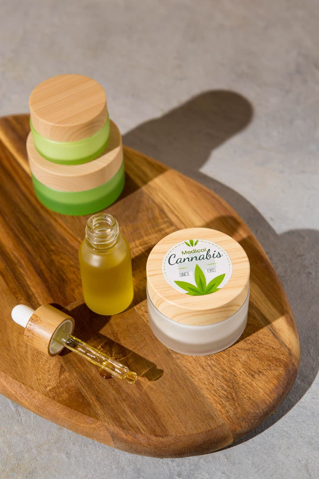 Cannabis topicals for joint pain relief, featuring jars and a dropper bottle on a wooden tray, emphasizing natural healing for inflammation and arthritis.