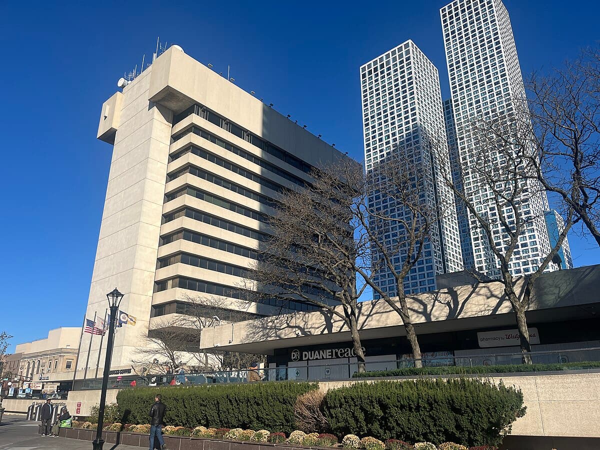 Uforia Dispensary location in Journal Square, Jersey City, featuring modern architecture, nearby trees, and local shoppers, with the Duane Reade store visible.